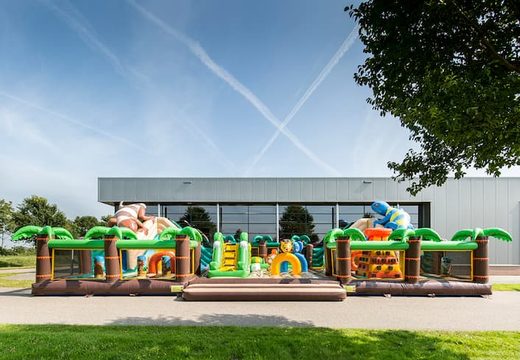 Colored inflatable park in jungle theme with slides, 3D objects, crawl tunnel and climbing tower for children. Buy bouncy castles online at JB Inflatables UK
